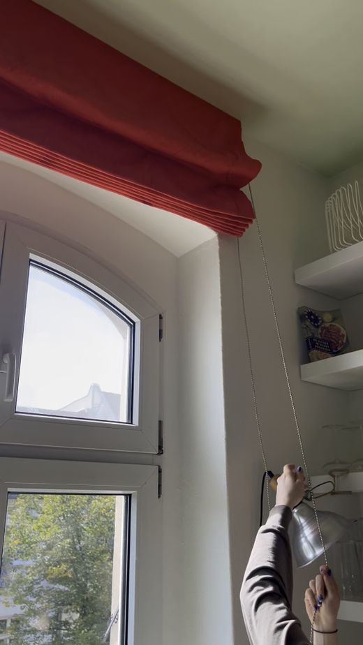 Rotes Raffrollo am Bogenfenster