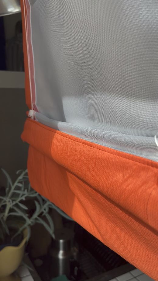 Detail des weiß-orangefarbenen Raffrollos