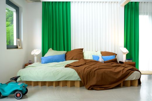 Schlafzimmer mit braunem Bett und grünem Vorhang